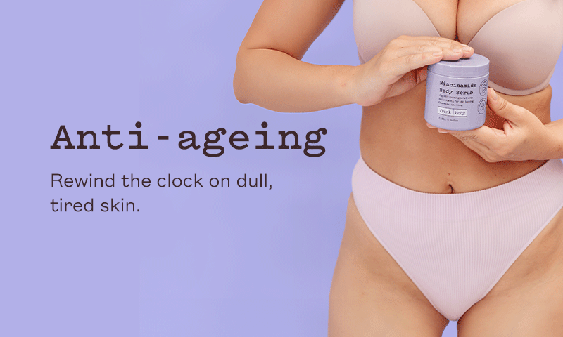 Anti-ageing collection banner. A woman in lilac underwear holding a tub of frank body Niacinamide Body Scrub. Text reads: Anti-ageing. Rewind the clock on dull, tired skin.