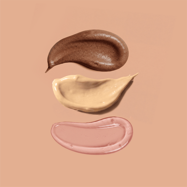 Swirls of frank body self tan mousse, tan butter and tanning jelly on a tan background.