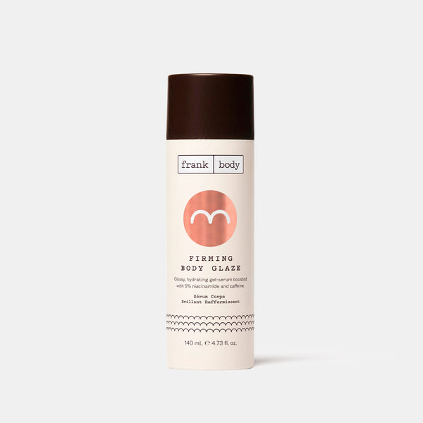 A cream bottle of frank body Firming Body Glaze with a black lid and copper motif on a white background.