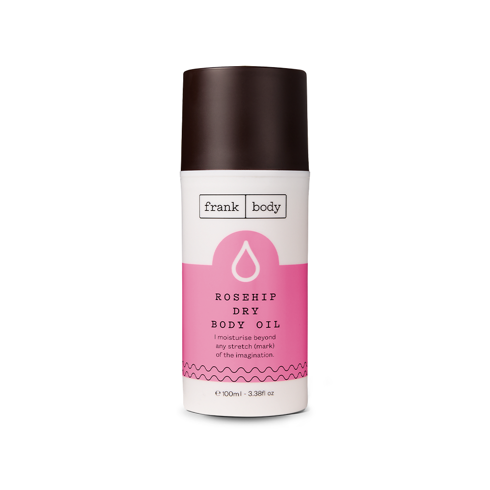 A bottle of frank body Rosehip Dry Body Oil with a dark cap and pink label, 100 ml, on a white background.