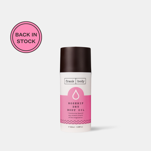 A white and pink bottle of frank body Rosehip Dry Body Oil, 100ml. Badge reads: Back in stock.